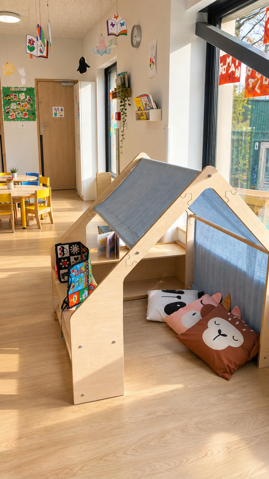 Espace de jeu lumineux avec une cabane en bois, coussins et coin lecture